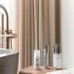 Skincare products including SPF sunscreen and serums displayed on a bathtub ledge, illustrating a spring skin care routine