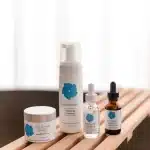 Lineup of Skin Benefit medical-grade skincare products, including a foaming cleanser, recovery cream, and serums, for skin care at every age
