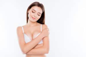 Woman in bra is very happy with her breast implant revision results.